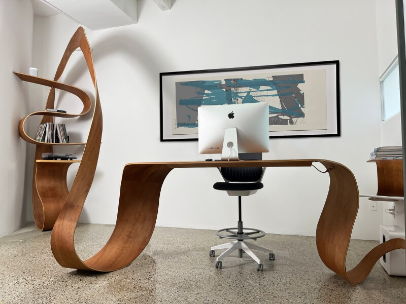 Ribbon Desk in office, curved cherry veneer desk with computer and ribbon shelving